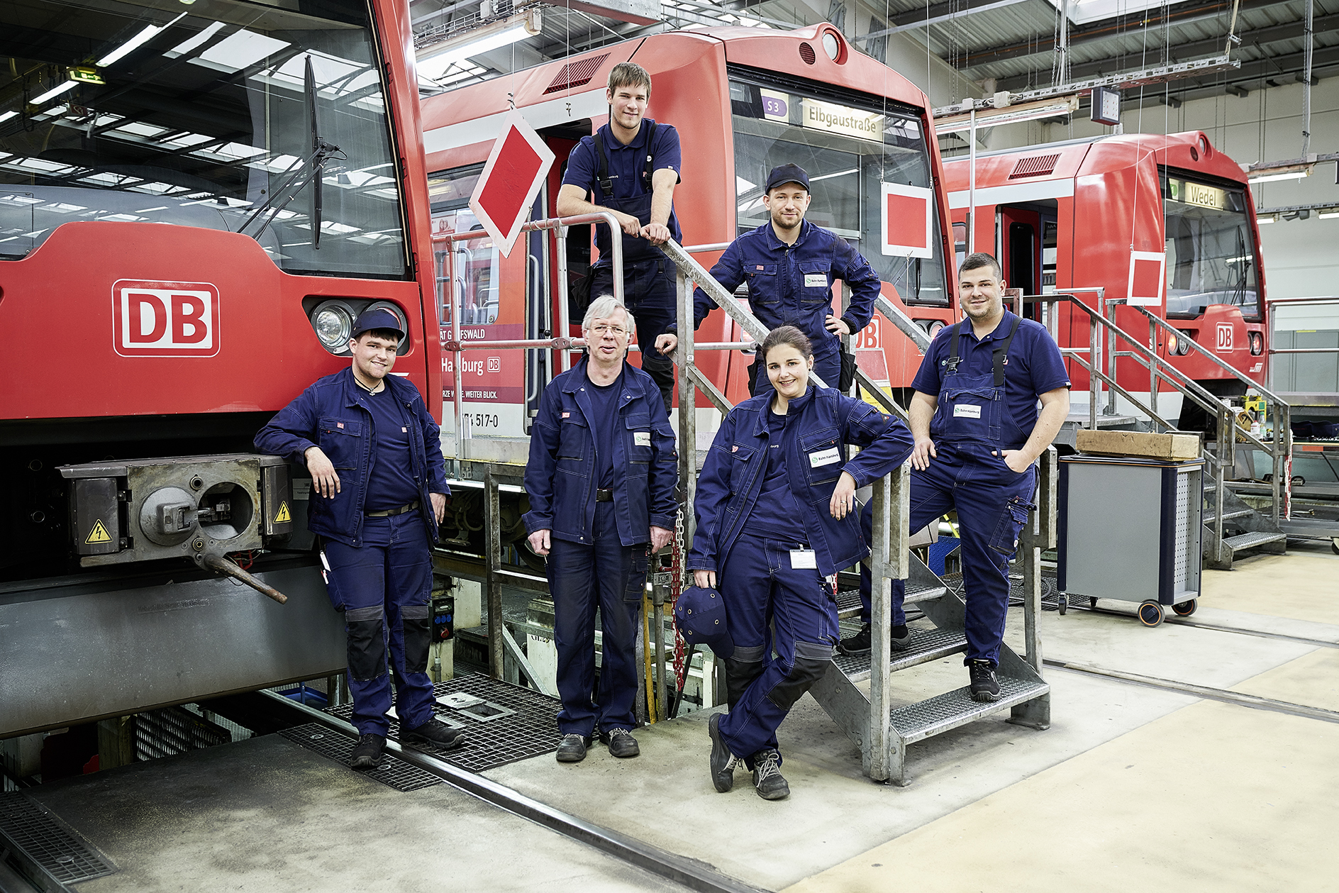 zu sehen sind Mitarbeitende der Deutschen Bahn vor roten Lokomotiven