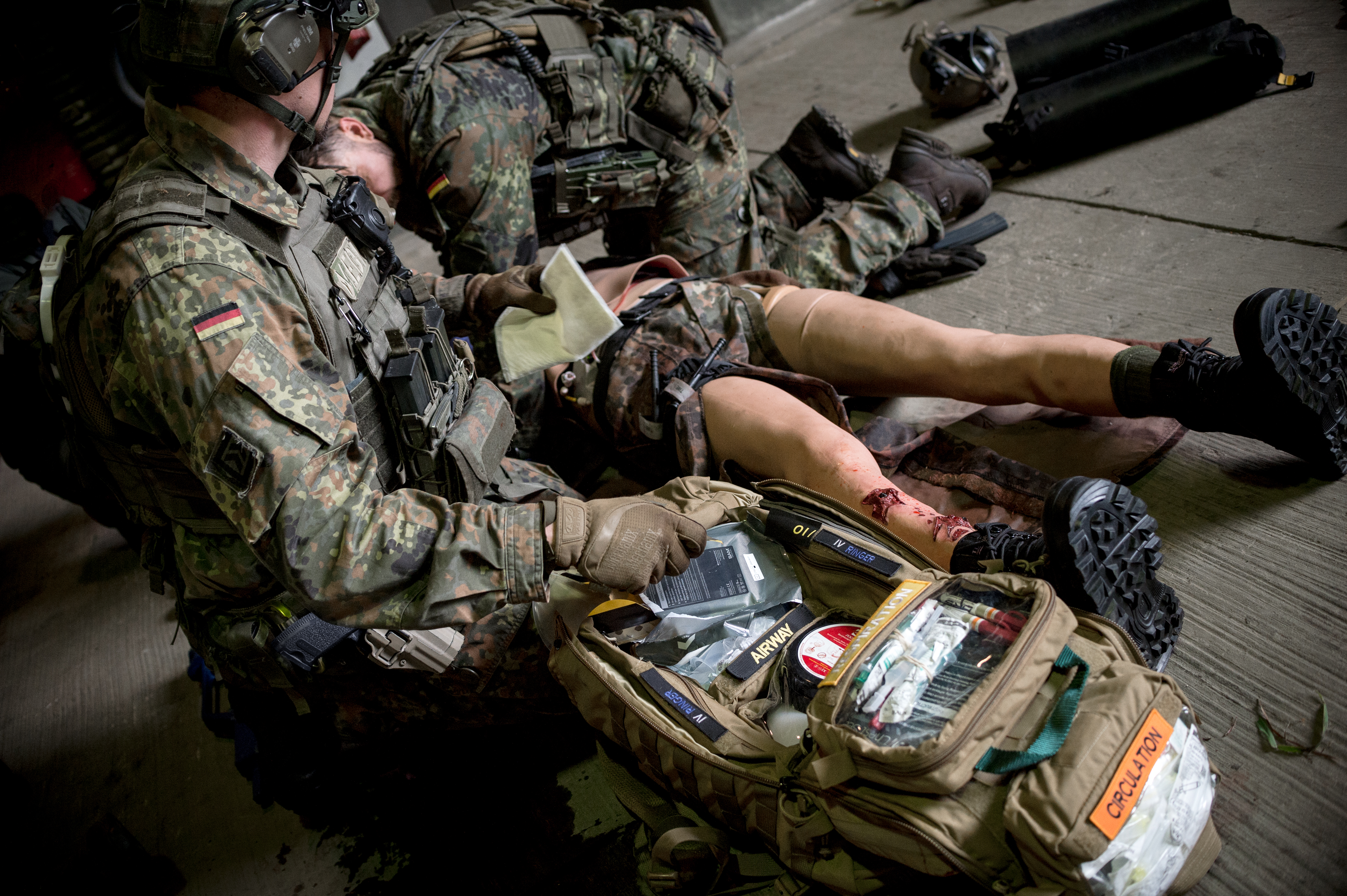 Während der Versorgung eines Verwundeten greift ein Kampfretter Material aus dem Sanitätsrucksack.