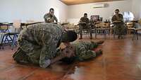 Ein Soldat beugt sich über den Übungspatienten um die Atmung zu kontrollieren