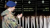 Soldatin zündet in Lourdes eine Gebetskerze an