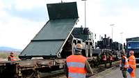 Ein Lastkraftwagen steht auf einem Eisenbahnflachwagen und setzt eine Transportplattform ab