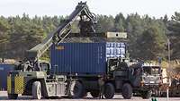 Ein Containerstapler hebt einen Container auf einen Lastkraftwagen.
