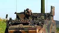 Ein Soldat mit Fernglas schaut aus der Luke eines Panzers mit Artilleriebeobachtungsradar ABRA