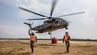 Ein Hubschrauber CH-53 mit rotem Behälter setzt zum Start an