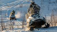 Zwei Soldaten fahren mit einem Ski-Doo durch den Schnee.