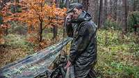 Ein Soldat im Wald am Funkgerät.