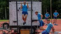 Soldaten machen Sport an Geräten auf einem Sportplatz.