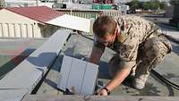 Ein Soldat schließt eine Antenne auf einem Containerdach an