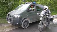 Kleinbus und Motorradstreife der Feldjäger nebeneinander vor einer grünen Hecke.