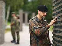 Ein Soldat berührt eine Namensstele im „Wald der Erinnerung“.