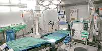 In der Mitte steht ein Operationstisch, um ihn herum mehre medizinische Geräte.