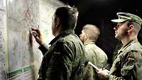 Zwei Soldaten stehen vor Lagekarten, einer gibt Anweisungen, ein anderer schreibt mit.