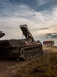 Ein Panzer steht bei Sonnenuntergang am Rande eines Übungsplatzes.