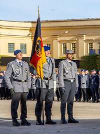 Drei Soldaten stehen im Dienstanzug in Grundform, der mittlere Soldat hält die Fahnenstange mit der Bundesdienstflagge