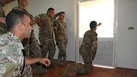 Soldaten im Unterrichtsraum. Ein Soldat hält im Knien den Arm an die Tür, um die mögliche Hitze zu spüren.