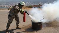 Ein libanesischer Soldat löscht mit einem Feuerlöscher ein kleines Feuer in einer Metalltonne