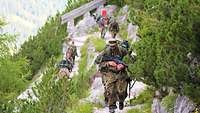 In Kolonne steigen Soldaten und ihre Maultiere auf den Berg. 