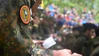 Soldat mit Lourdes-Wappen beim Gottesdienst im Zeltlager