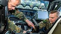 Zwei Soldaten befestigen IT-Technik im Fond eines Militärfahrzeuges.