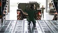Ein Soldat weist ein gepanzertes Fahrzeug beim Einparken in den Cargo#en Hold#en Trainer#en ein.
