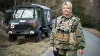 Eine Soldatin steht mit Schutzweste vor einem Krankentransportwagen der Bundeswehr