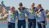 Vier Frauen in Sportanzügen mit Goldmedaillen um den Hals.