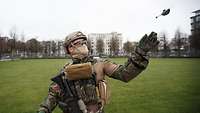 Ein Soldat steht auf einer Freifläche und lässt mit der linken Hand die Drohne in die Luft.