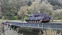 Ein Panzer rollt über eine Metallbrücke von einem zum anderen Ufer.