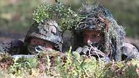 Zwei Soldaten im Feldanzug in einem Alarmposten im Wald.