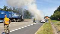 Brennendes Auto steht am Seitenstreifen und wird gelöscht.