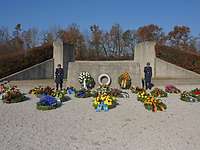Frontalblick auf das Ehrenmal der Luftwaffe, an dem mehrere Kränze liegen und zwei Soldaten stehen.