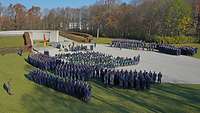 Blick auf das Ehrenmal der Luftwaffe mit angetretenen Soldaten und sitzenden Personen davor.