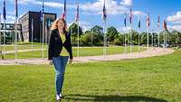 Sylvia Göhler vor dem Hauptquartier in Brunssum. Hinter ihr sieht man das Gebäude und Flaggen von NATO-Staaten.