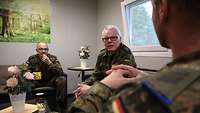 Drei Soldaten sitzen beisammen und unterhalten sich
