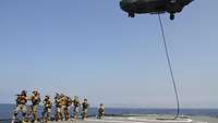 Mehrere Soldaten laufen an Deck eines Schiffes hintereinander