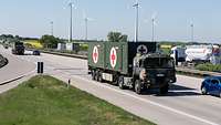 Ein ungeschütztes Militärisches Transportfahrzeug fährt – im Bild von links nach rechts kommend – auf einer Autobahnstrecke.