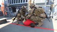 Zwei Soldaten haben einen Zivilisten zu Boden gebracht und legen ihm Handfesseln an