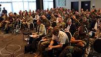 Viele Personen sitzen in einem Saal.