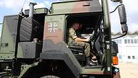 Im Fahrerhaus eines LKW sitzt ein Soldat und arbeitet an einem Touchpad