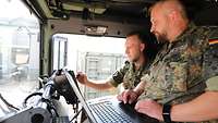 Zwei Soldaten im Fahrerhaus vor Laptop und neuem Touchscreen