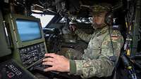 Ein Soldat sitzt in einem Spähwagen Fennek vor einem Bildschirm.