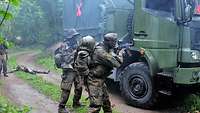 In strömendem Regen zwingen Soldaten einen Lkw mit vorgehaltenen Waffen zum Stehen.