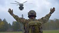 Ein Objektschützer weist den Hubschrauber CH-53 ein