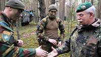 Zwei Soldaten reichen sich die Hände, dabei liegt in der Hand des Inspekteurs ein Coin, eine Münze.