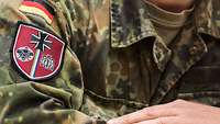 Militärisch gekleidete Person mit Wappen der Schule ABC-Abwehr und Gesetzliche Schutzaufgaben am Ärmel.