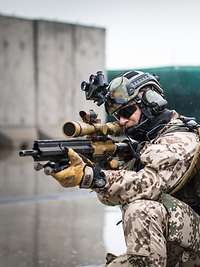 Zwei Soldaten knien auf dem nassen Boden mit der Waffe im Anschlag.