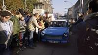 Ein Trabant wird am Grenzübergang von Menschen empfangen.