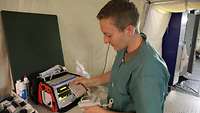 Eine Krankenpflegerin steht an einem Defibrillator und prüft die Funktion der Sensoren
