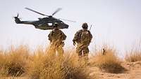 Zwei Soldaten vor einem Hubschrauber in der malischen Wüste von Gao