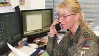 Eine Soldatin telefoniert am Schreibtisch.